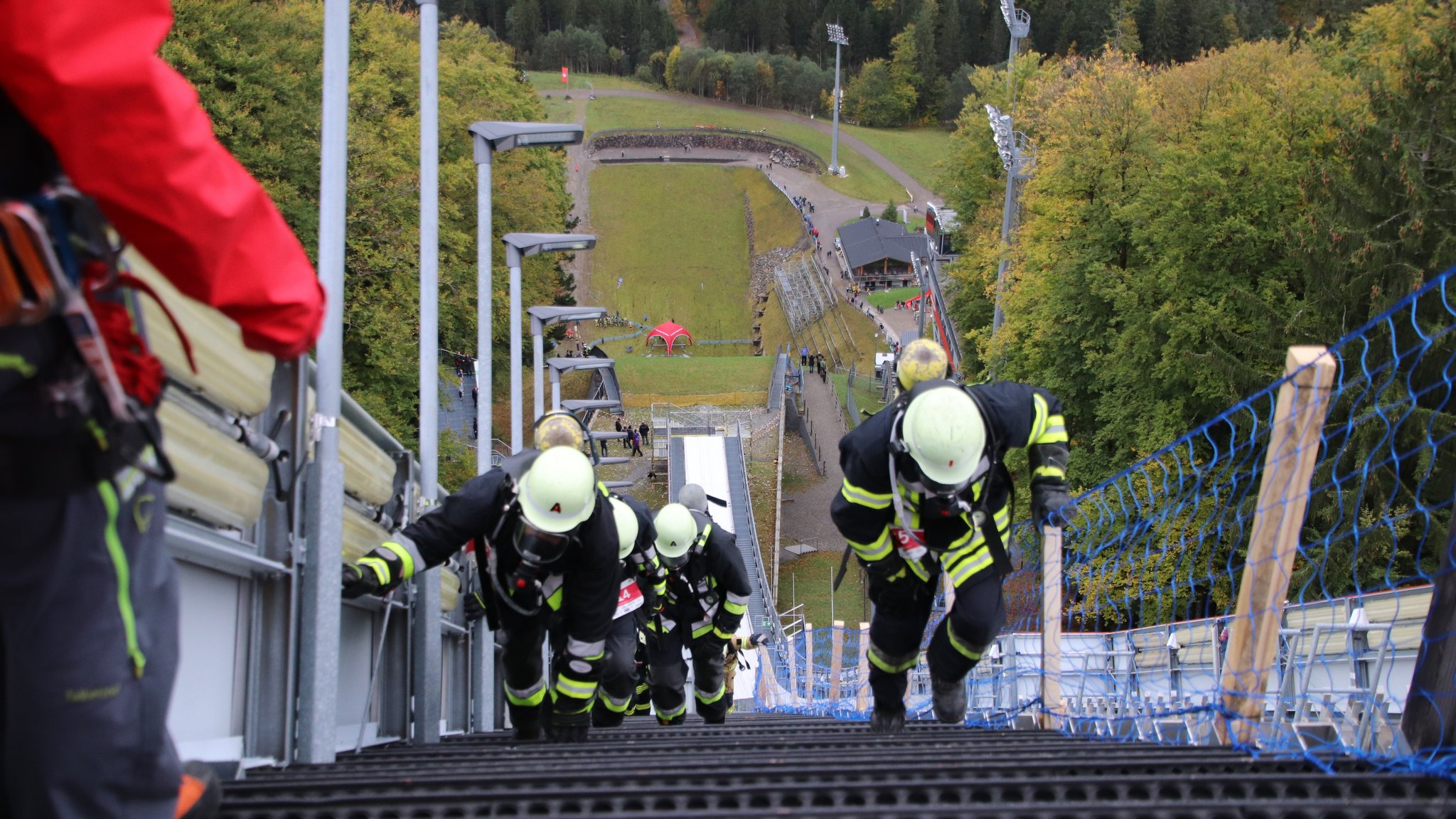 (Archivbild) Feuerwehrleute steigen in voller Bandschutzmontur bei einem Schanzenlauf die 1.000 Stufen der Heini-Klopfer-Schanze hinauf.