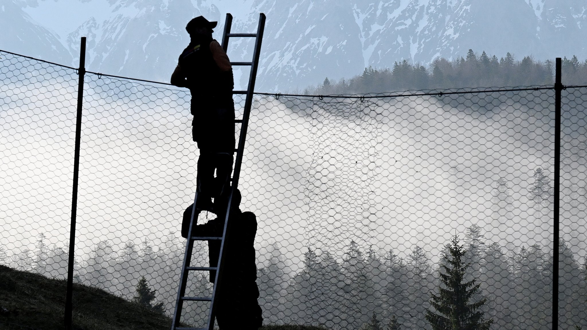 Arbeiter bauen im Wald rund um Schloss Elmau den Sperrzaun für den G7-Gipfel auf, im Hintergrund ist das Wettersteingebirge zu sehen. 