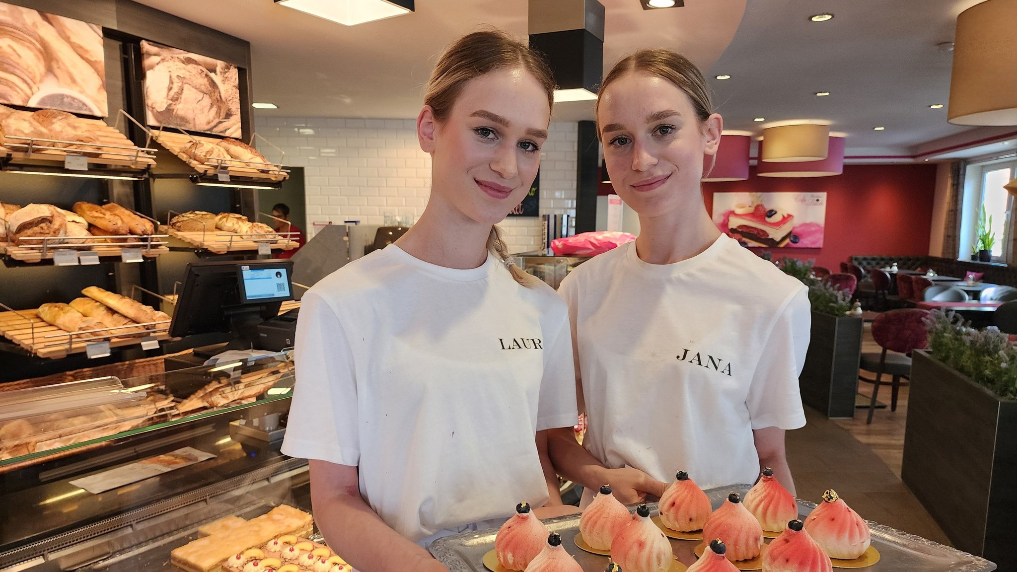 Die Zwillinge Laura und Jana Hofmann halten ein Tablett mit Törtchen in der Hand.