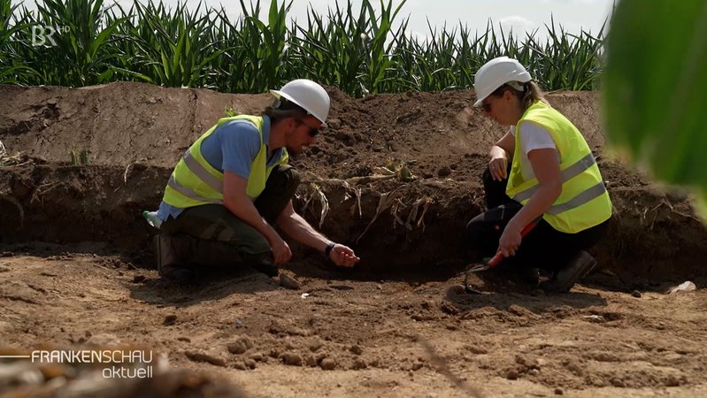 Zwei Archäologen graben im Boden.