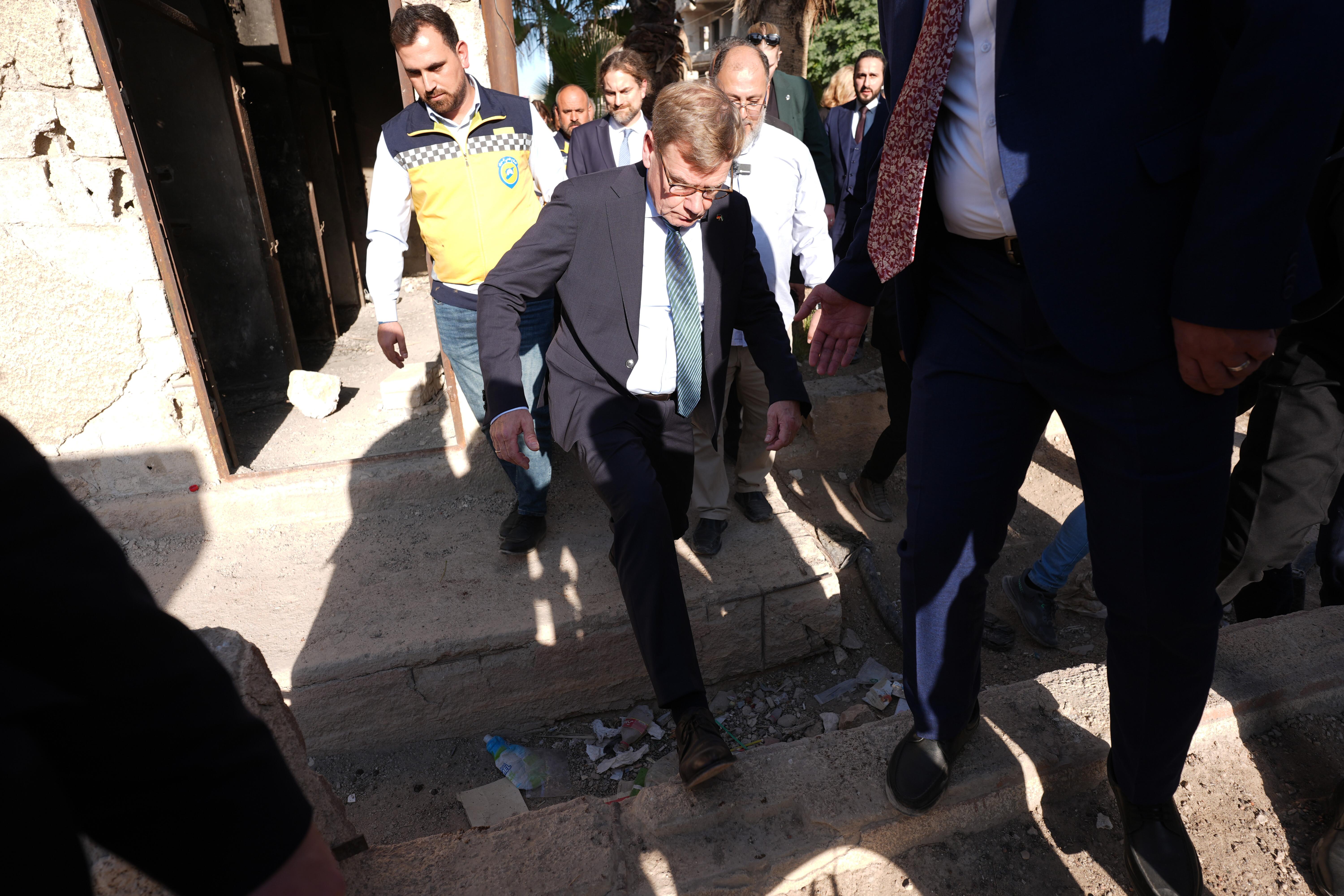 Außenminister Johann Wadephul (CDU) springt über einen Graben während seines Besuchs eines humanitären Projekts in Harasta in einem während des Bürgerkriegs zerbombten Stadtteil.