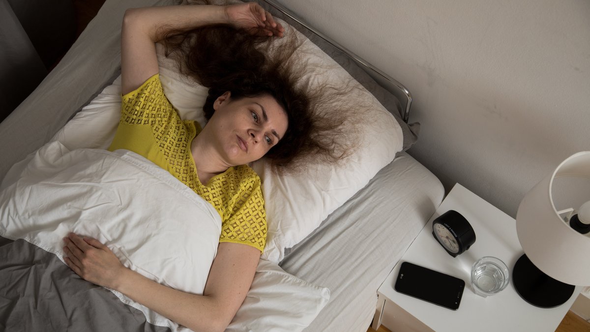 Eine Frau liegt wach im Bett (gestellte Szene)