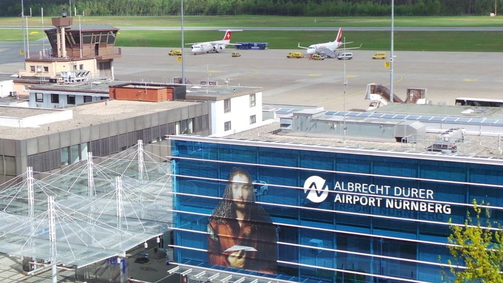 Ein Blick auf Tower, Flugzeuge und die Abflughalle von oben. 