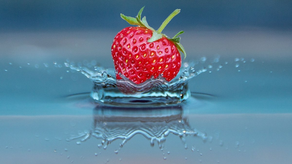 Eine Erdbeere kurz vor dem Eintauchen in das Wasser. 