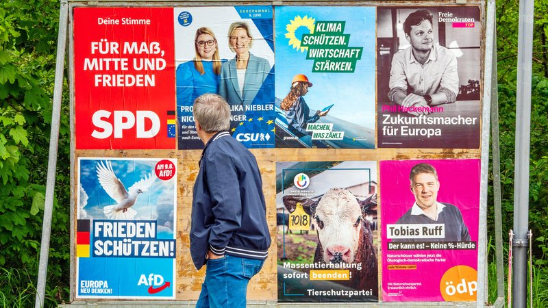 Mann steht vor Wahlplakaten in Bayern zur Europawahl.