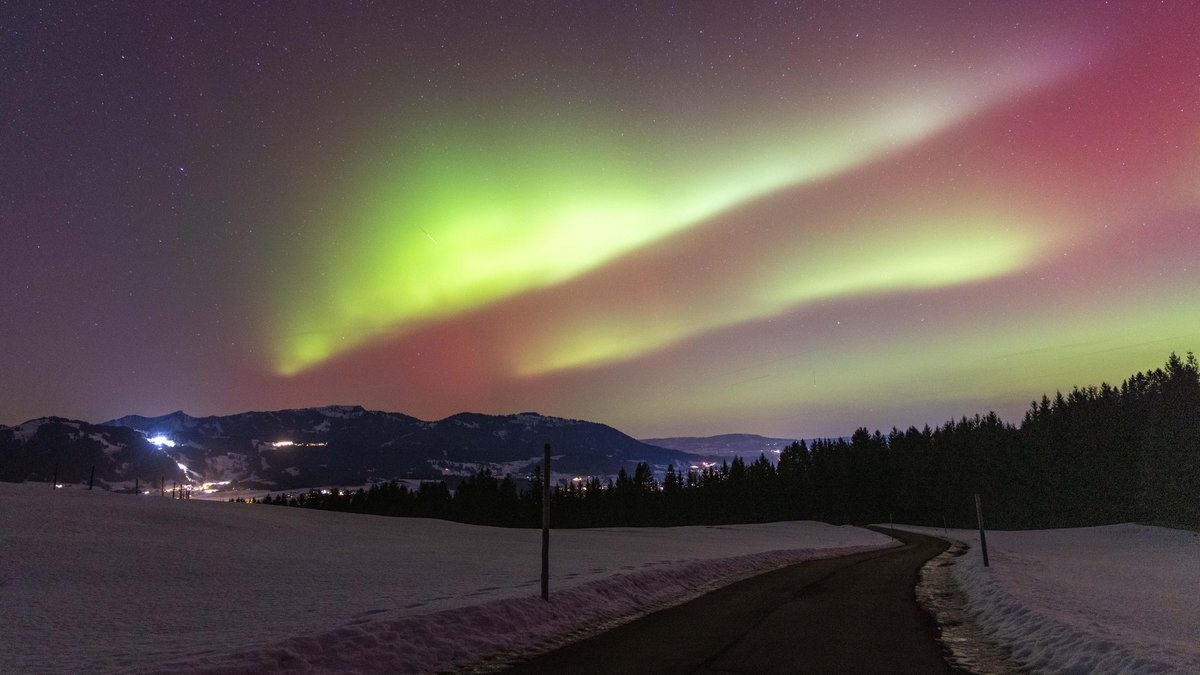 Polarlichter sind in der Nacht über der Landschaft im Oberallgäu mit den Bergen der Hörnerkette zu sehen.