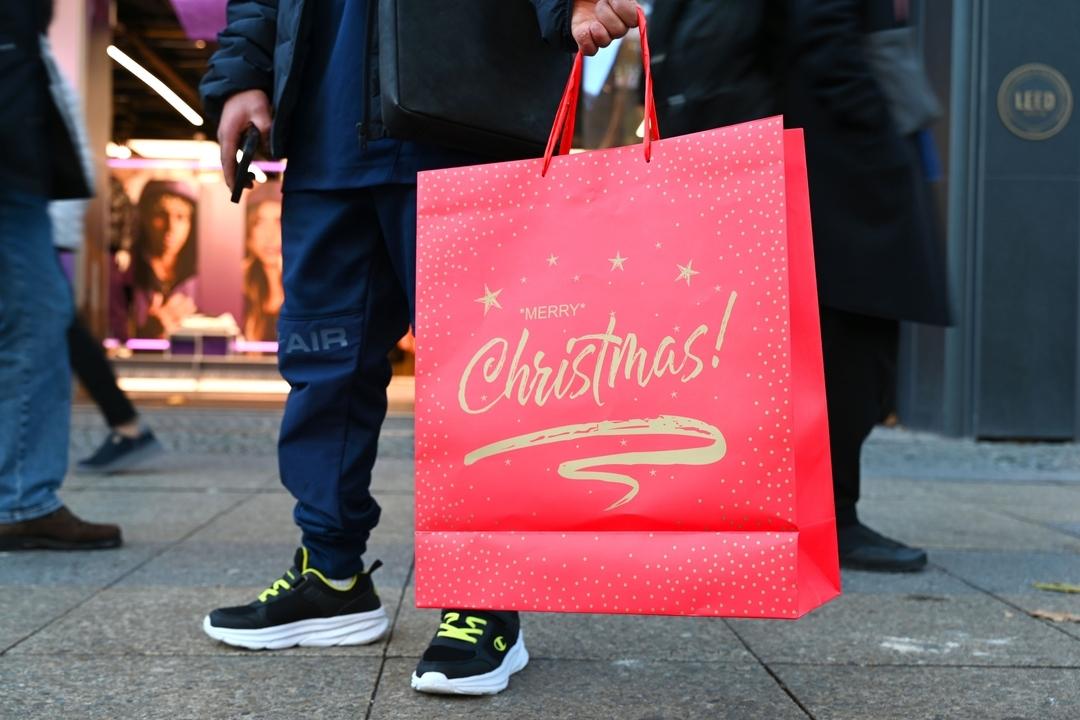 Ein Mann zeigt eine rote Tasche mit der Aufschrift "Merry Christmas"