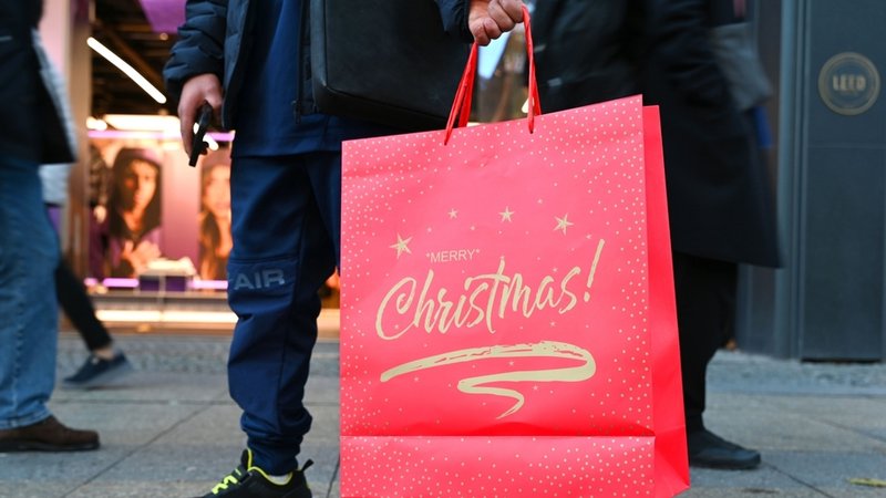 Ein Mann zeigt eine rote Tasche mit der Aufschrift "Merry Christmas" | Bild: dpa-Bildfunk/Elisa Schu Ein Mann zeigt eine rote Tasche mit der Aufschrift "Merry Christmas"