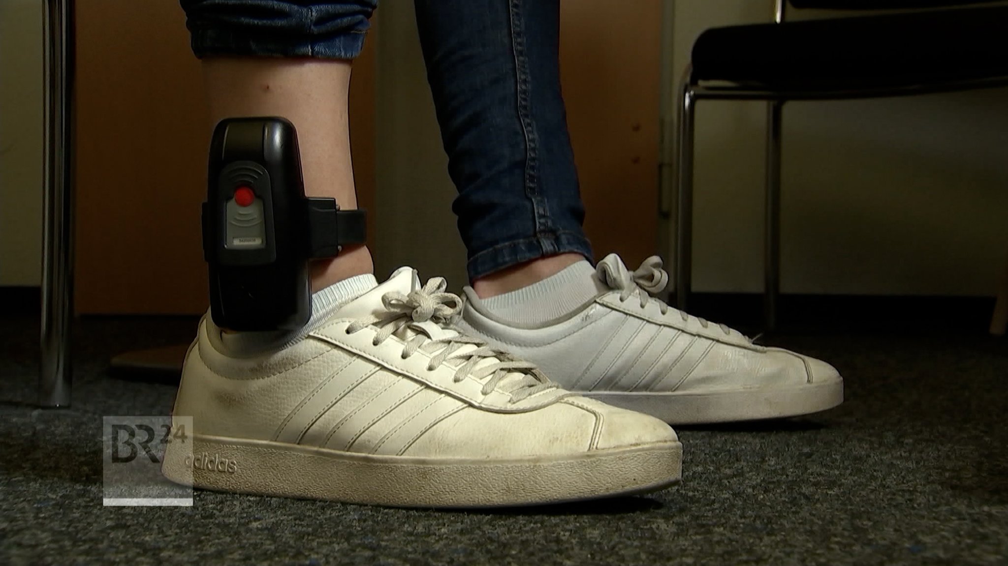 Person in weißen Turnschuhen und Jeanshose trägt Füßfessel | Bild: BR Person in weißen Turnschuhen und Jeanshose trägt Füßfessel
