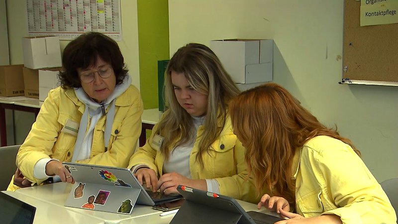 Drei Frauen in gelber Jeansjacke.
