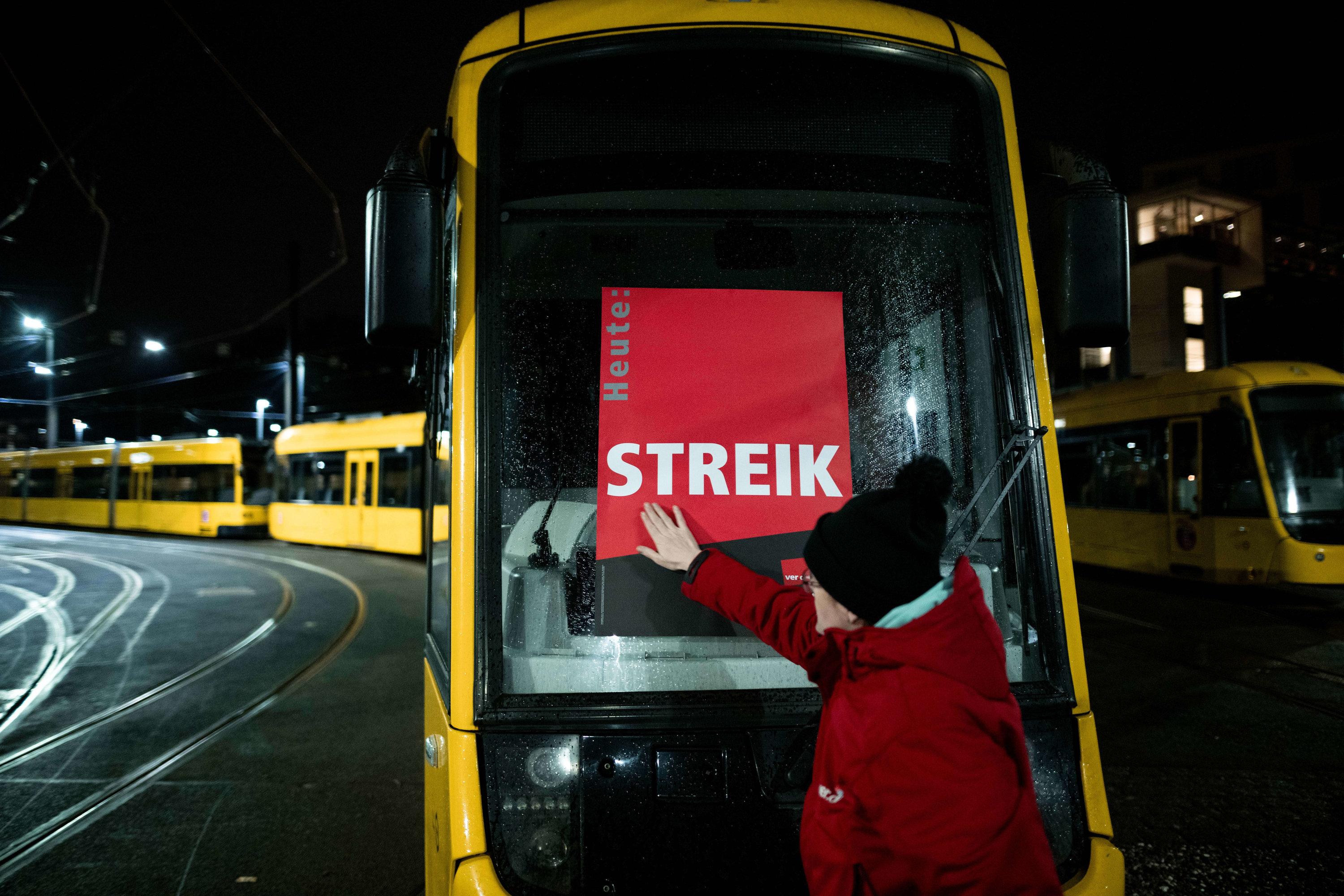Eine Mitarbeiterin klebt ein Poster, auf dem "Heute: STREIK" steht, auf eine Trambahn im Depot der Ruhrbahn in Essen (Archivfoto)