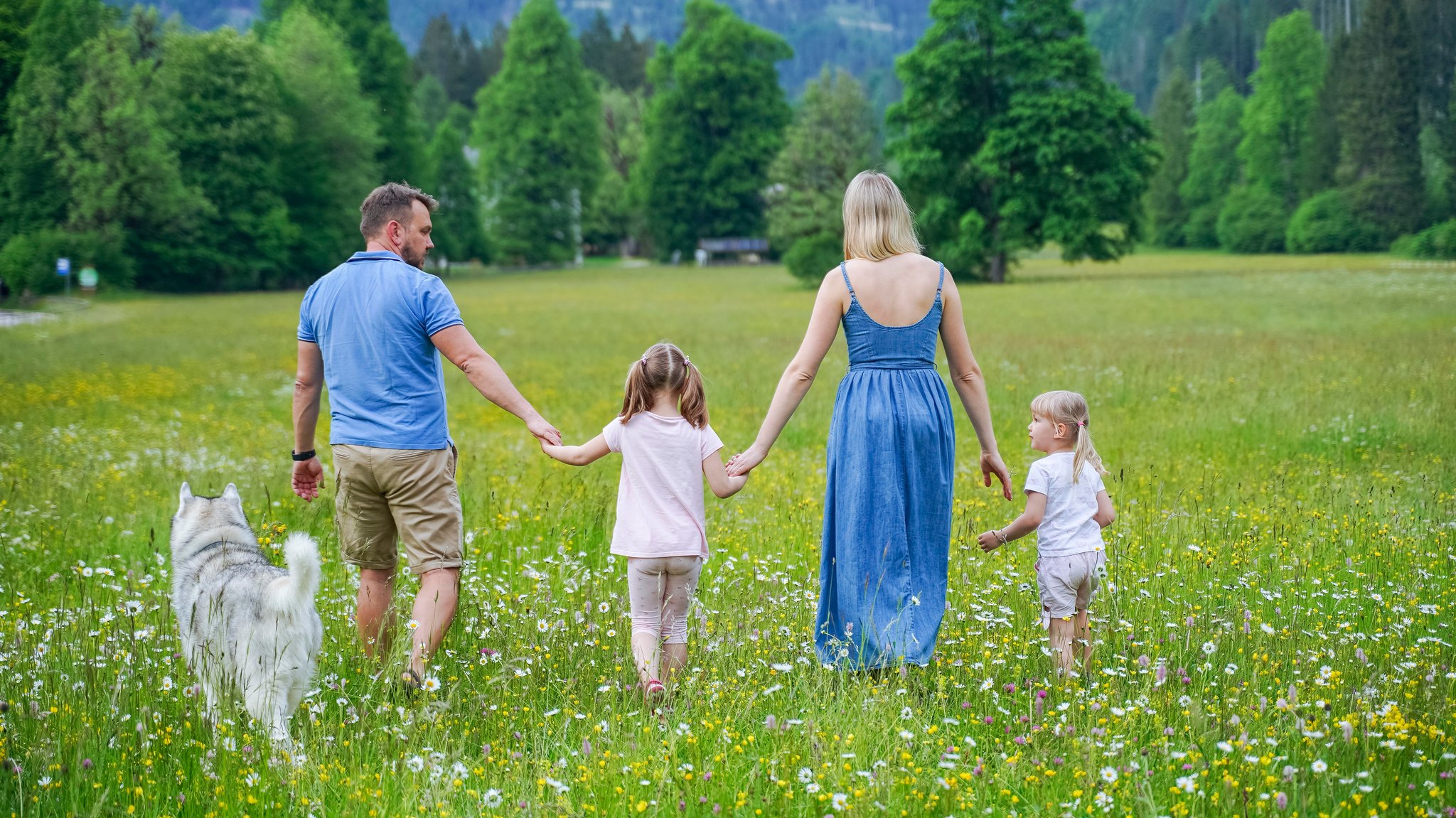 Eine Familie geht über eine Wiese.