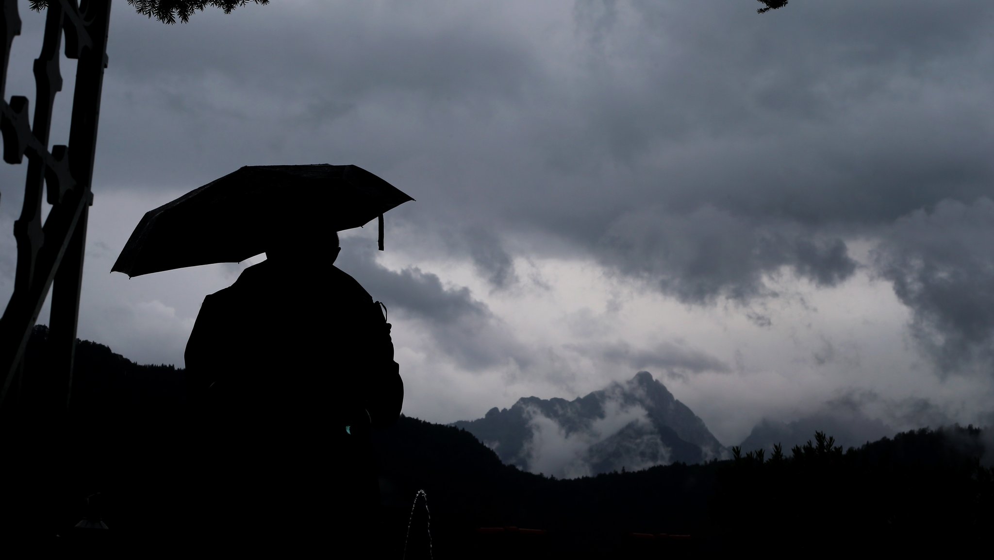 Symbolbild: Eine Person mit Regenschirm mit Blick auf die Berge