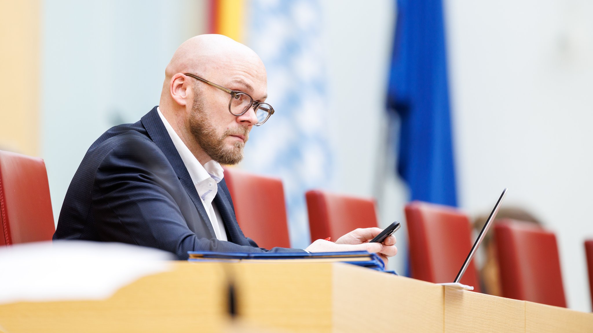 Fabian Mehring (Freie Wähler), Digitalminister von Bayern, blickt in einer Plenarsitzung im Bayerischen Landtag auf sein Smartphone.