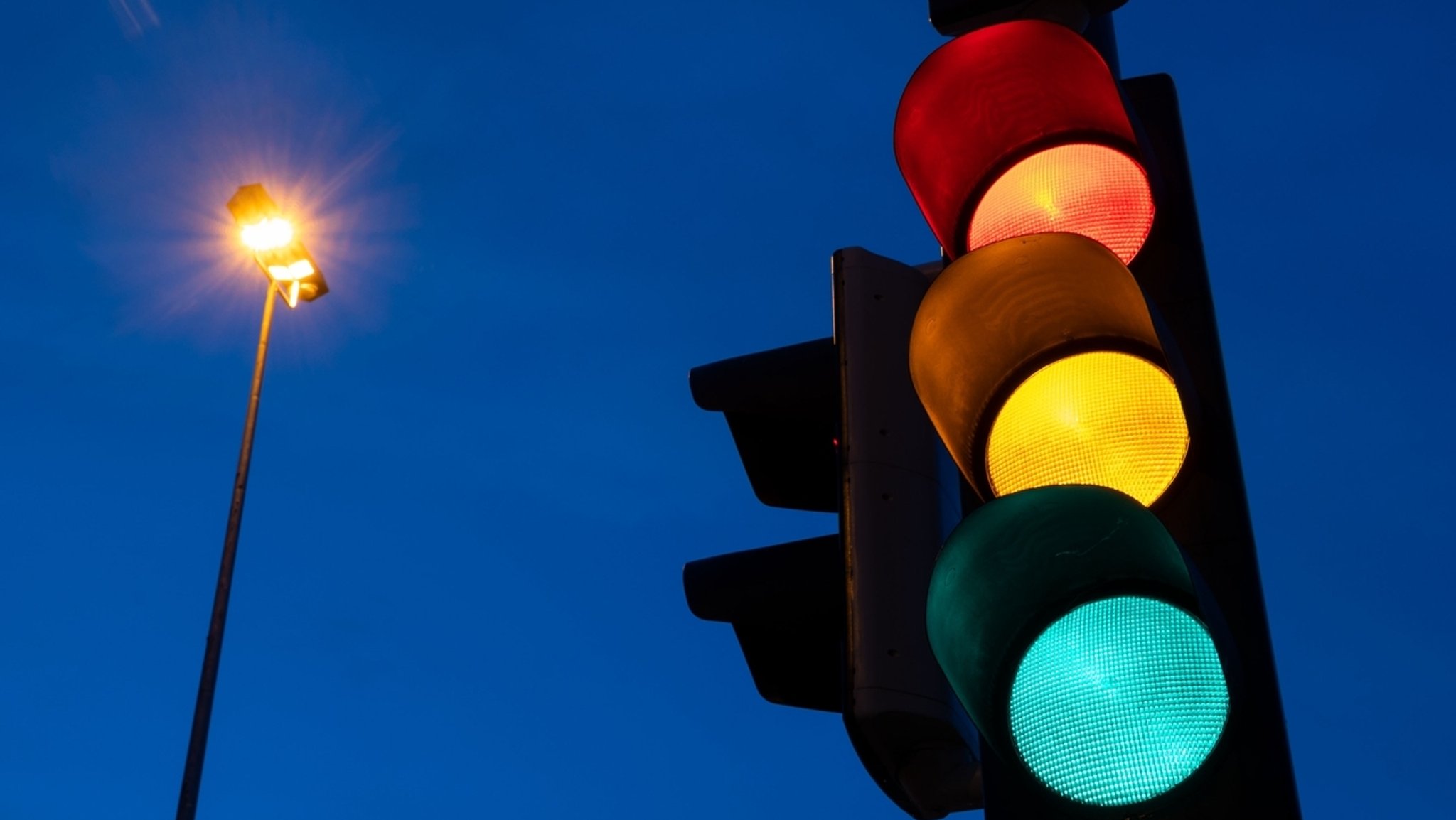 Eine Ampel zeigt am frühen Morgen die Farben rot, gelb und grün 