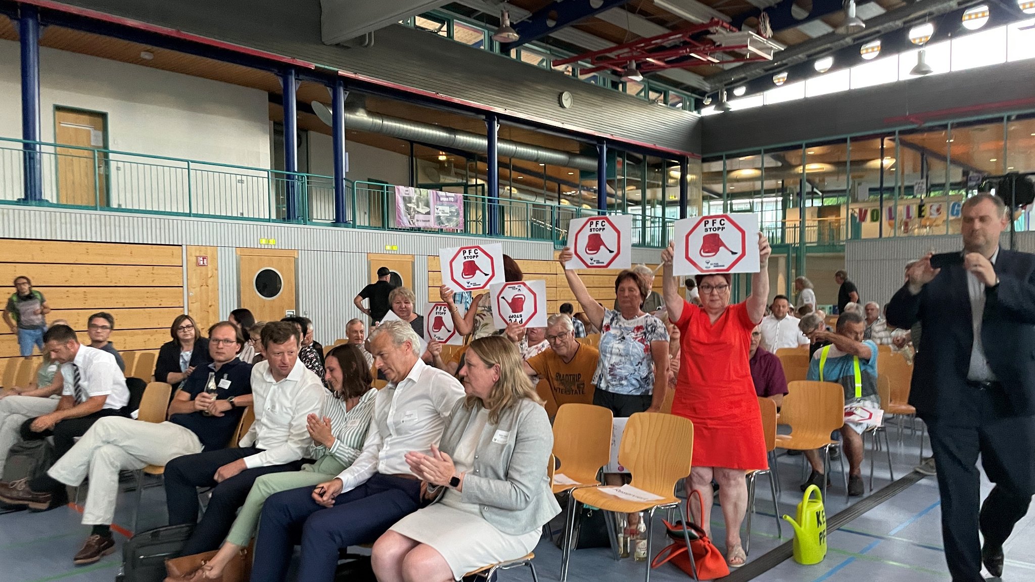 Mitglieder der Bürgerinitiative "NO PFAS Manching" halten bei der Infoveranstaltung Protestplakate hoch