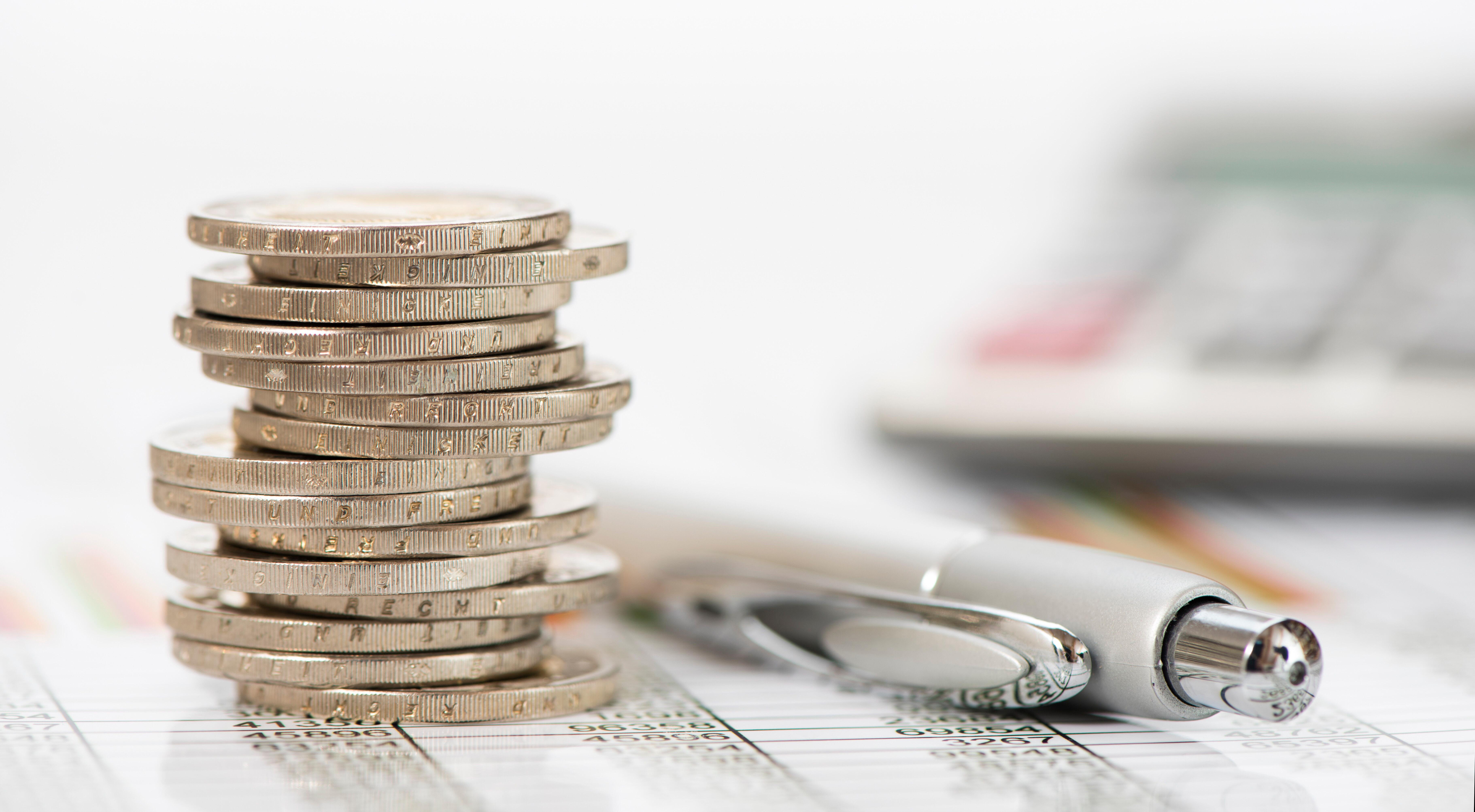 Ein Stapel Euromünzen und Kugelschreiber liegt auf einem Chart