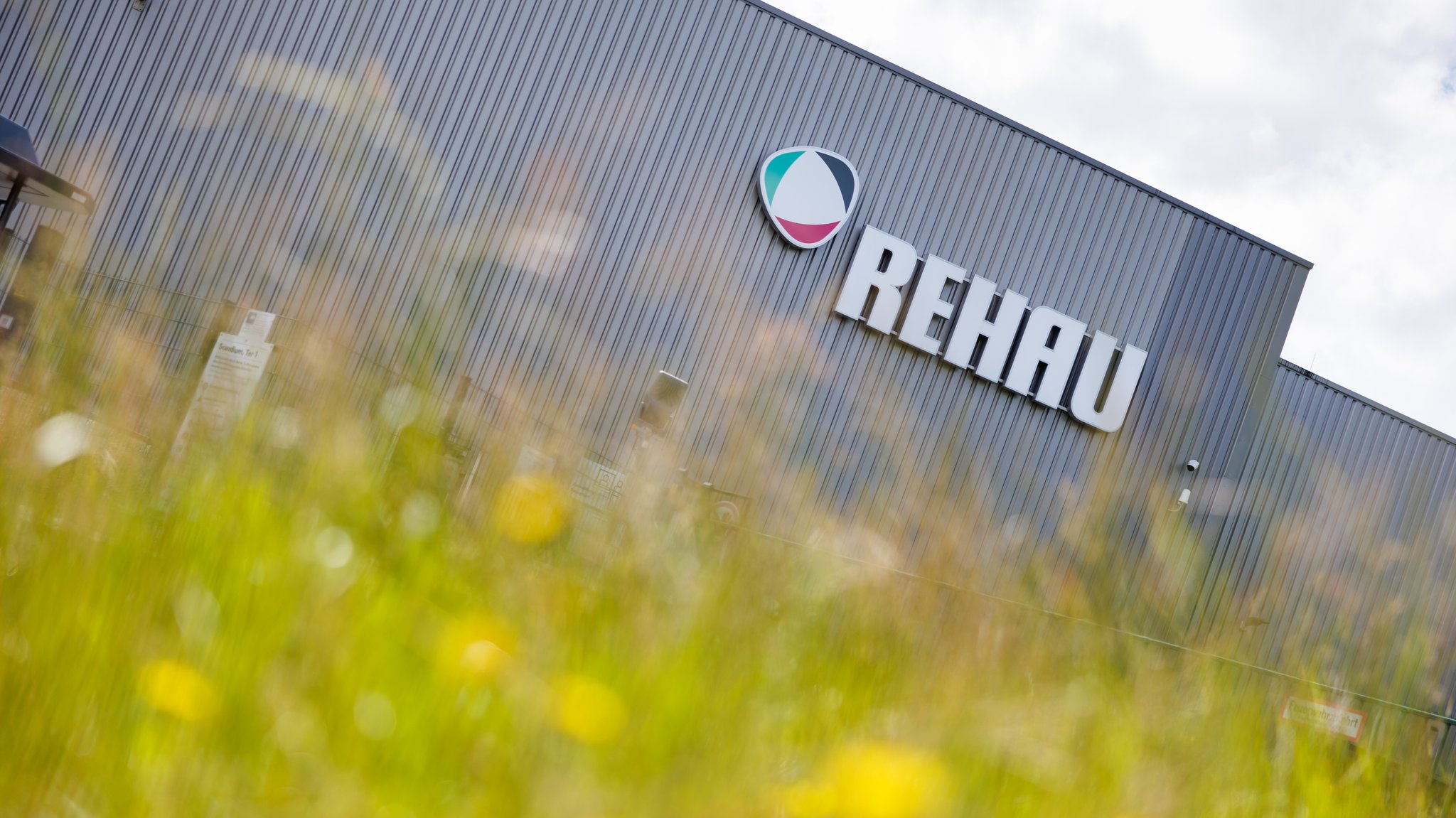 Der Schriftzug "Rehau" ist an einer Halle vom Werk Scandium der REHAU Industries SE & Co. KG in Rehau (Bayern) zu sehen.