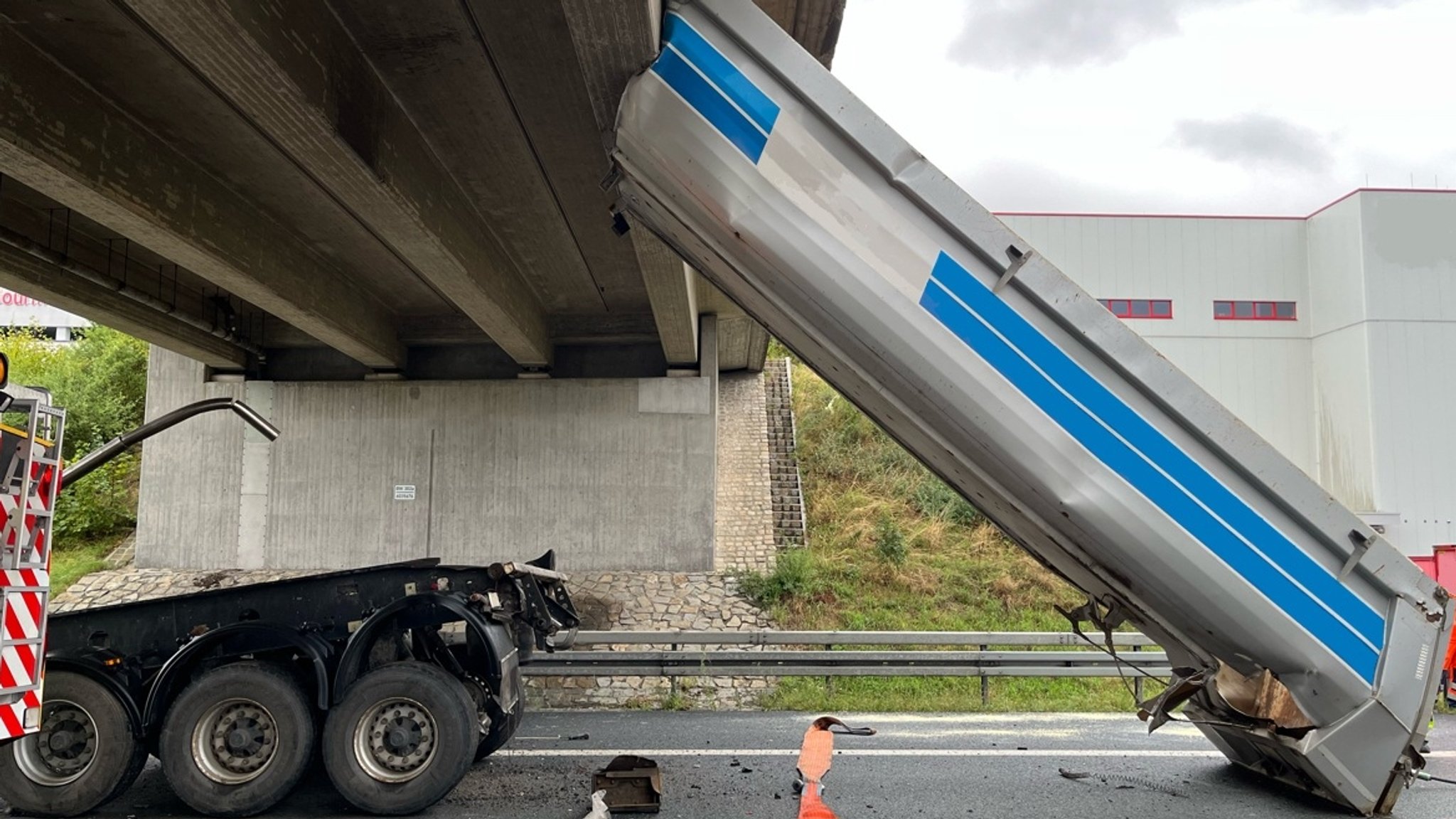 Die hochgeklappte Mulde eines Lkw ist an einer Brücke hängen geblieben. Am Boden liegen einzelne Trümmer. | Bild: Polizei Die hochgeklappte Mulde eines Lkw ist an einer Brücke hängen geblieben. Am Boden liegen einzelne Trümmer.