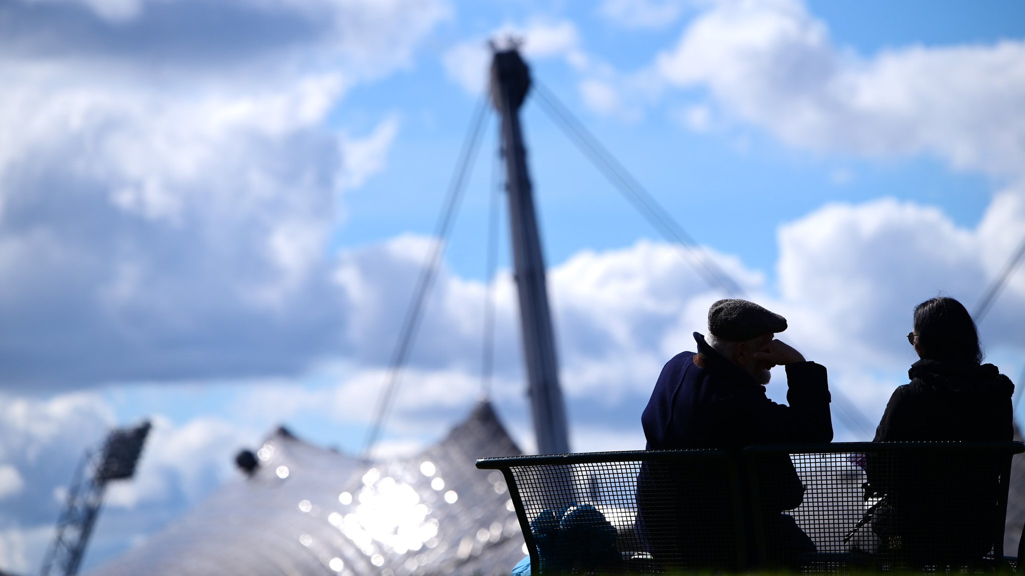  Ein Mann und eine Frau sitzen auf einer Bank im Münchner Olympiapark. 