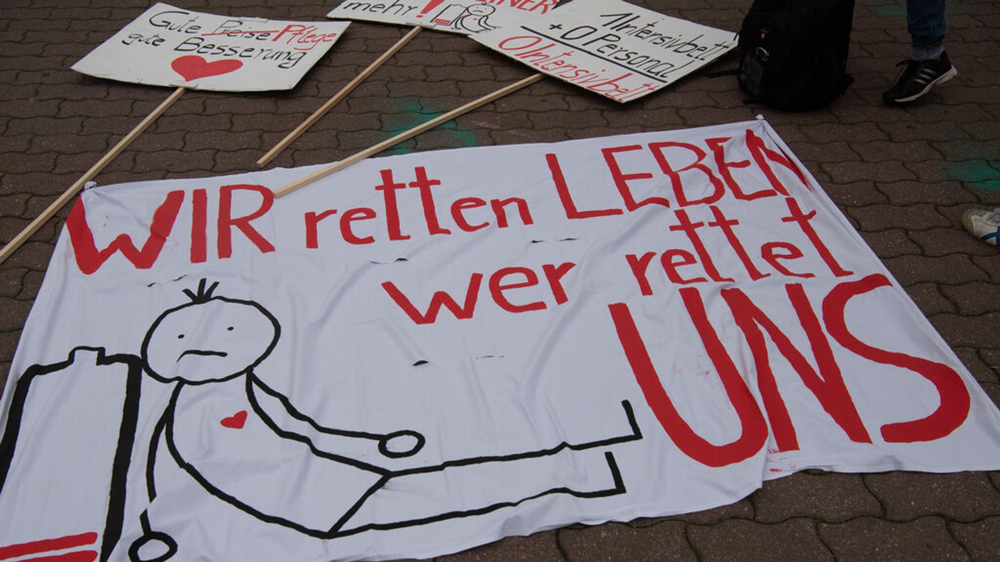 ARCHIV - 12.05.2021, Berlin: "WIR retten Leben - wer rettet UNS" steht auf einem Transparent bei einer Protestveranstaltung der Gewerkschaft verdi am Neptunbrunnen. Dort trafen sich zahlreiche Mitarbeiter aus dem medizinischen Pflegebereich. (zu dpa: «Diakonie und Caritas fordern Hilfe für die Altenpflege») Foto: Paul Zinken/dpa-Zentralbild/dpa +++ dpa-Bildfunk +++