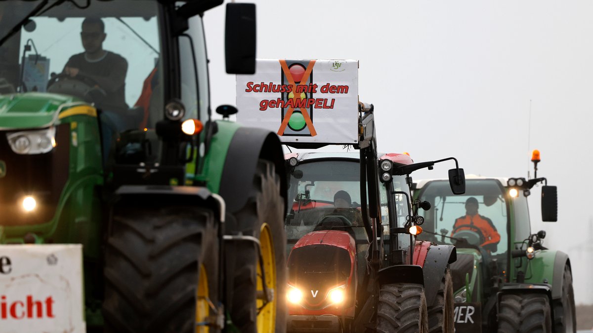 Teilnehmer der Bauernproteste fahren in Köln mit ihren Traktoren im Korso und präsentieren dabei Schilder mit Aufschriften, die Schluss mit der ideologischen Politik und das Ende der Ampel fordern.
