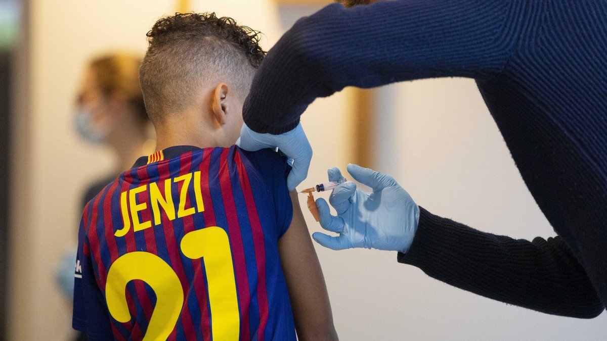 Junge von hinten in einem Fussballtrikot bekommt eine Impfung.