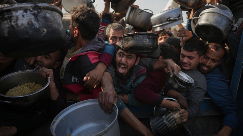 Palästinensische Gebiete, Chan Junis: Menschen drängen sich mit Töpfen in der Hand Verteilungszentrum, um eine Portion Nahrung zu bekommen. | Bild: dpa-Bildfunk/Abdel Kareem Hana Palästinensische Gebiete, Chan Junis: Menschen drängen sich mit Töpfen in der Hand Verteilungszentrum, um eine Portion Nahrung zu bekommen.