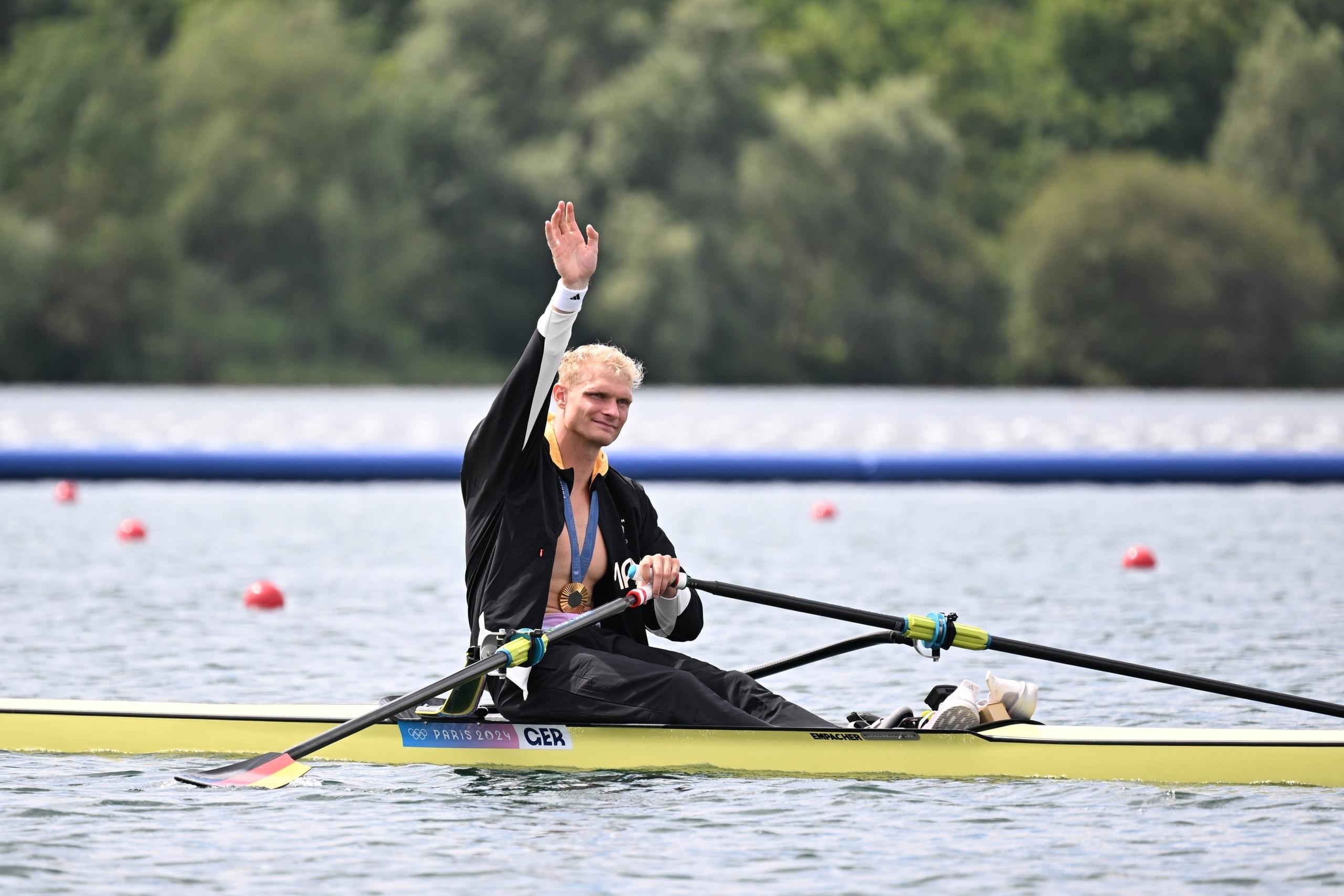 03.08.2024, Frankreich, Vaires-Sur-Marne: Olympia, Paris 2024, Rudern, Einer, Männer, Finale, Vaires-sur-Marne Nautical Stadium, Oliver Zeidler aus Deutschland sitzt nach der Siegerehrung in seinem Boot und winkt. 