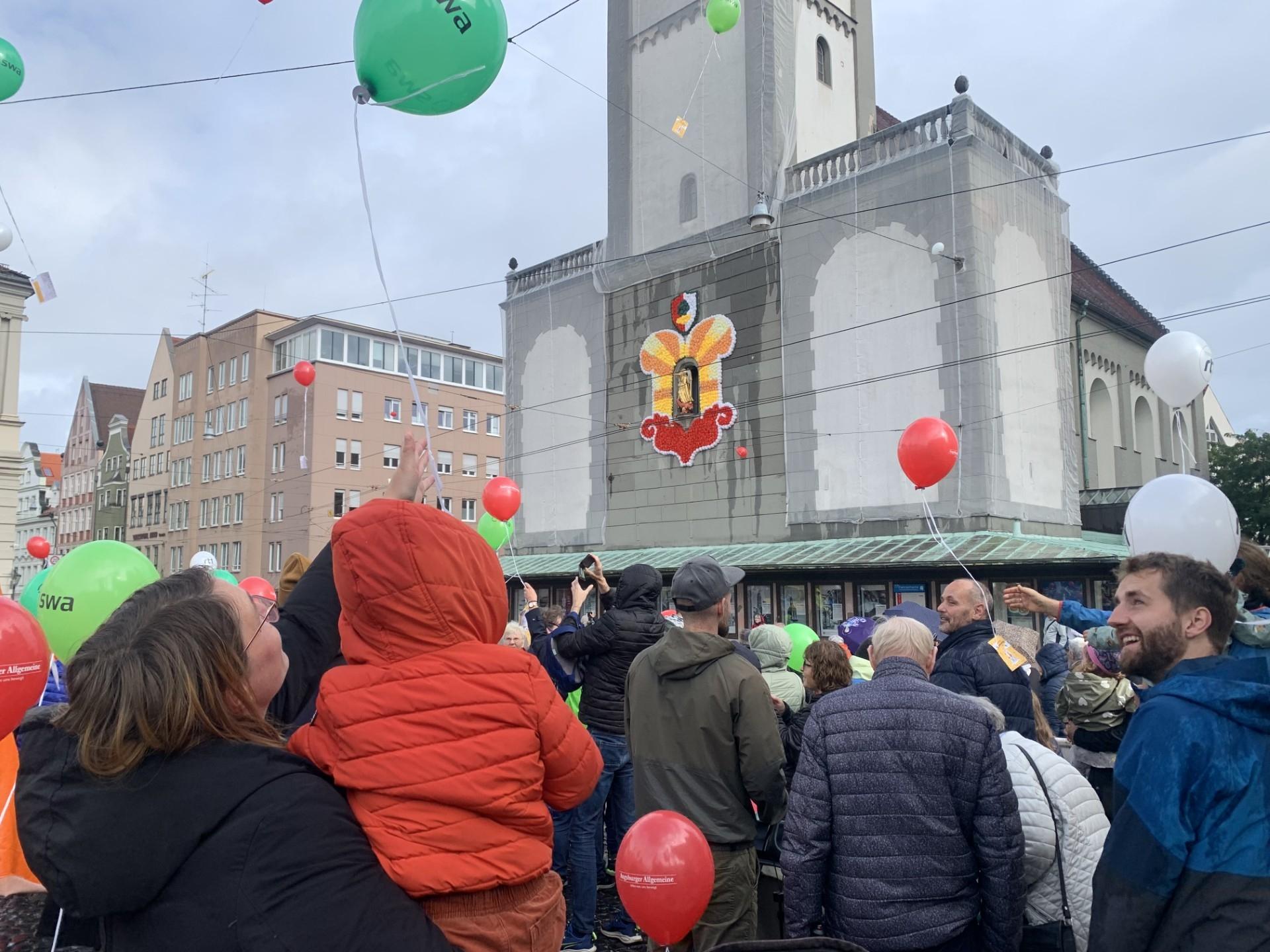 Beim Turamichelefest in Augsburg steigen rote, grüne und weiße Luftballone auf (Samstag, 28.09.2024).