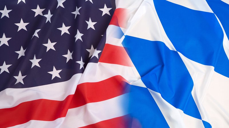 Fotomontage: Eine US-amerikanische und eine bayerische Flagge wehen. | Bild: BR Fotomontage: Eine US-amerikanische und eine bayerische Flagge wehen.