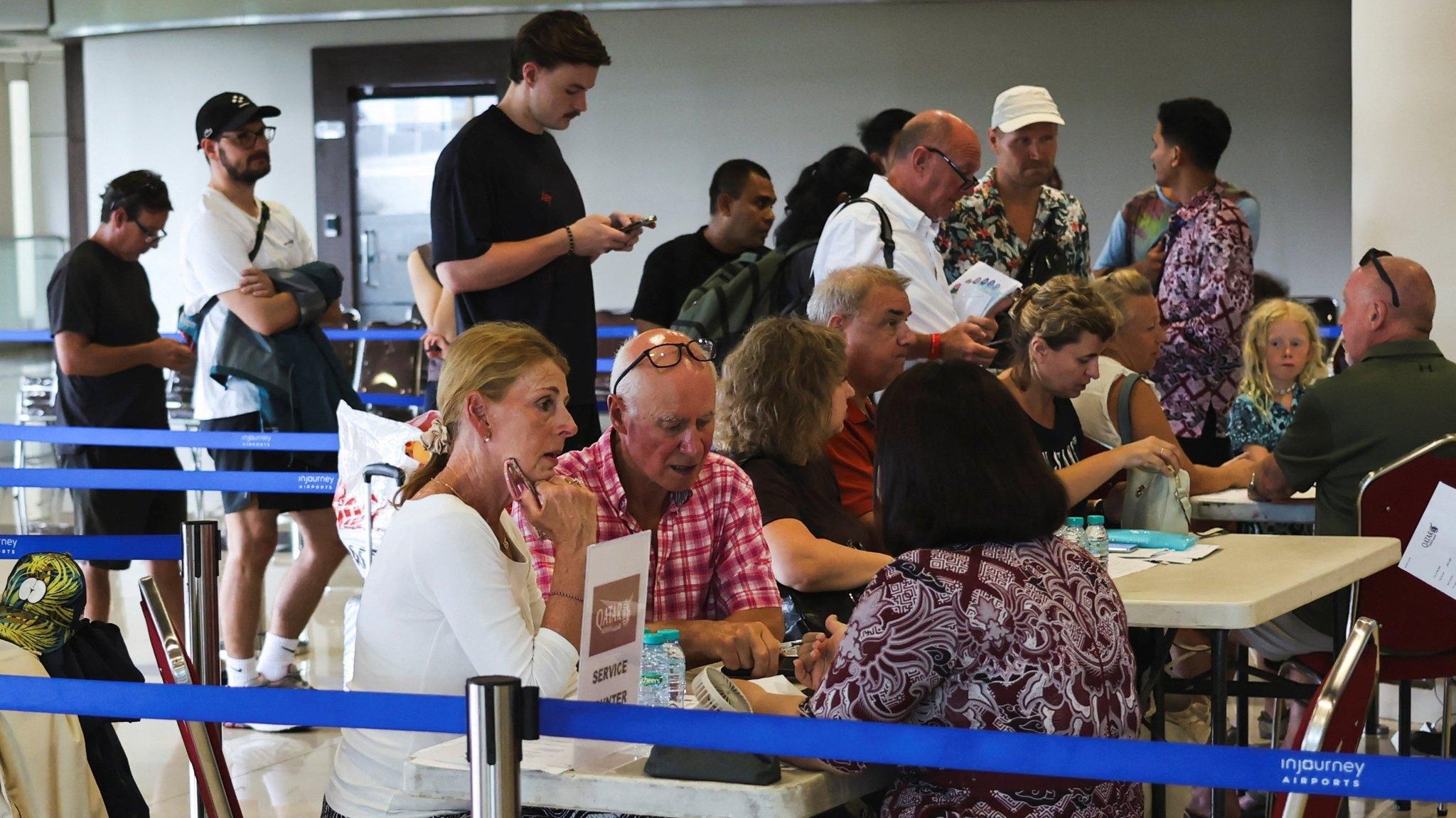 Urlauber sitzen an Info-Tischen am Flughafen Dubai.