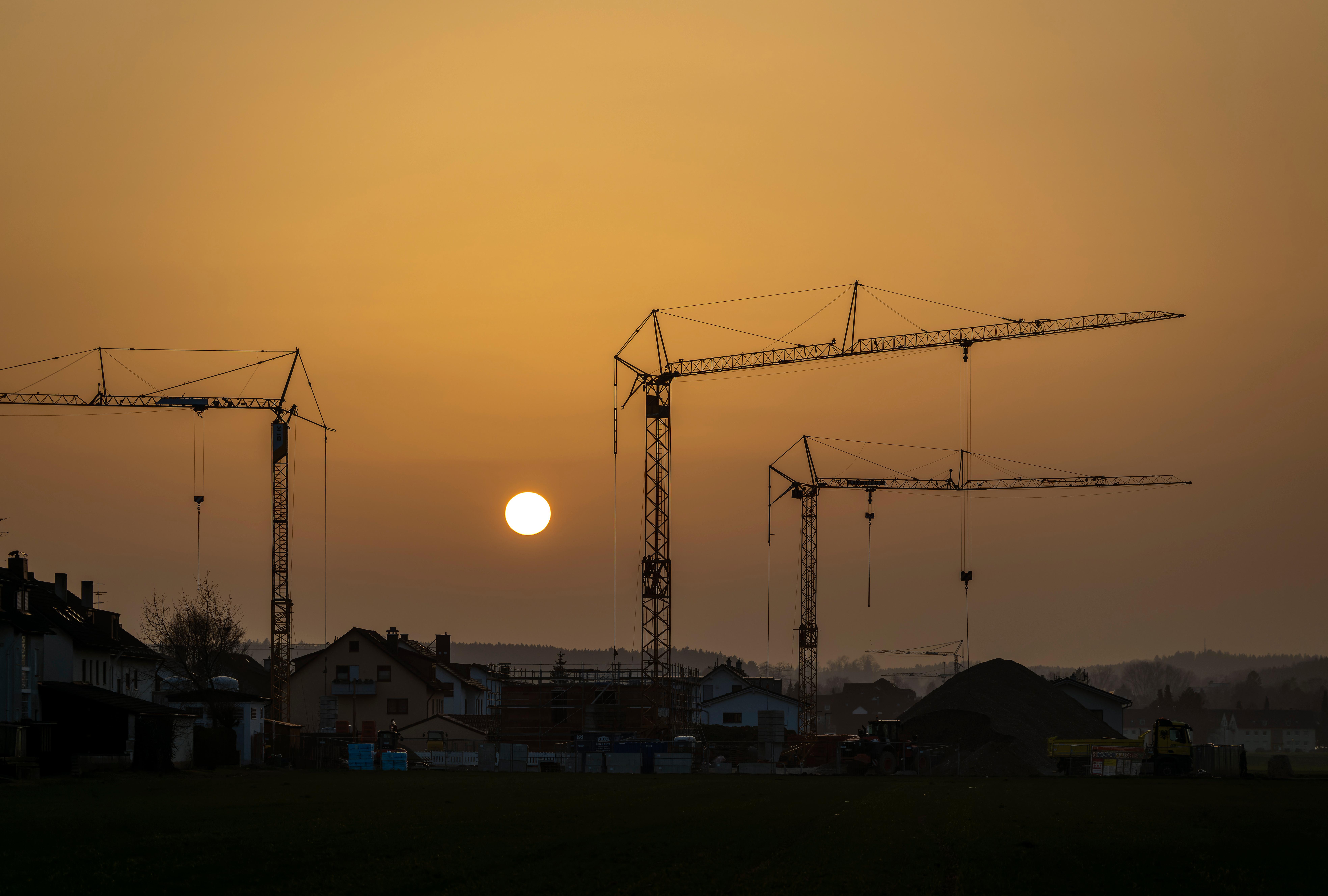 Die Sonne geht als glutroter Ball hinter einer Baustelle in der Gartenstadt unter.