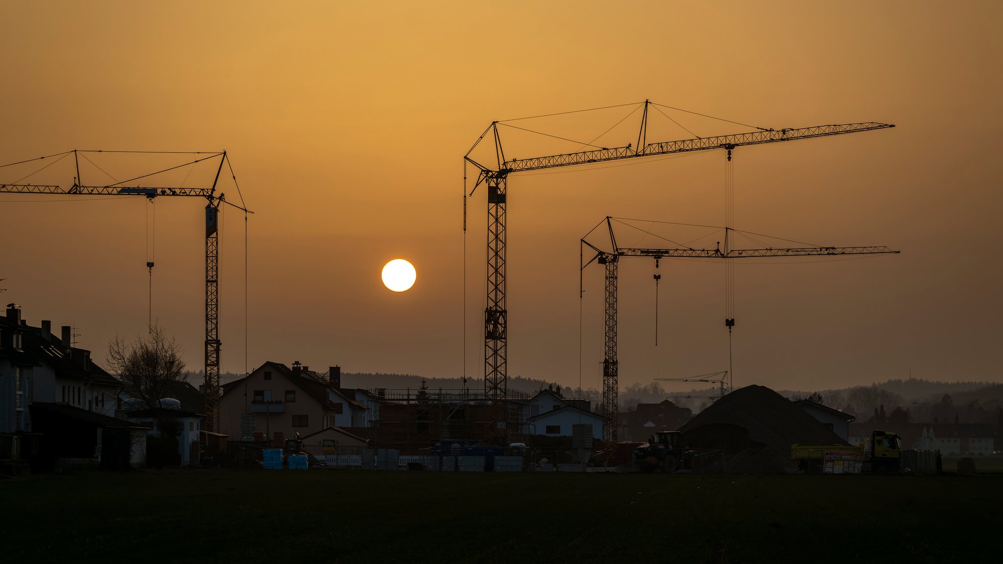 Die Sonne geht als glutroter Ball hinter einer Baustelle in der Gartenstadt unter.