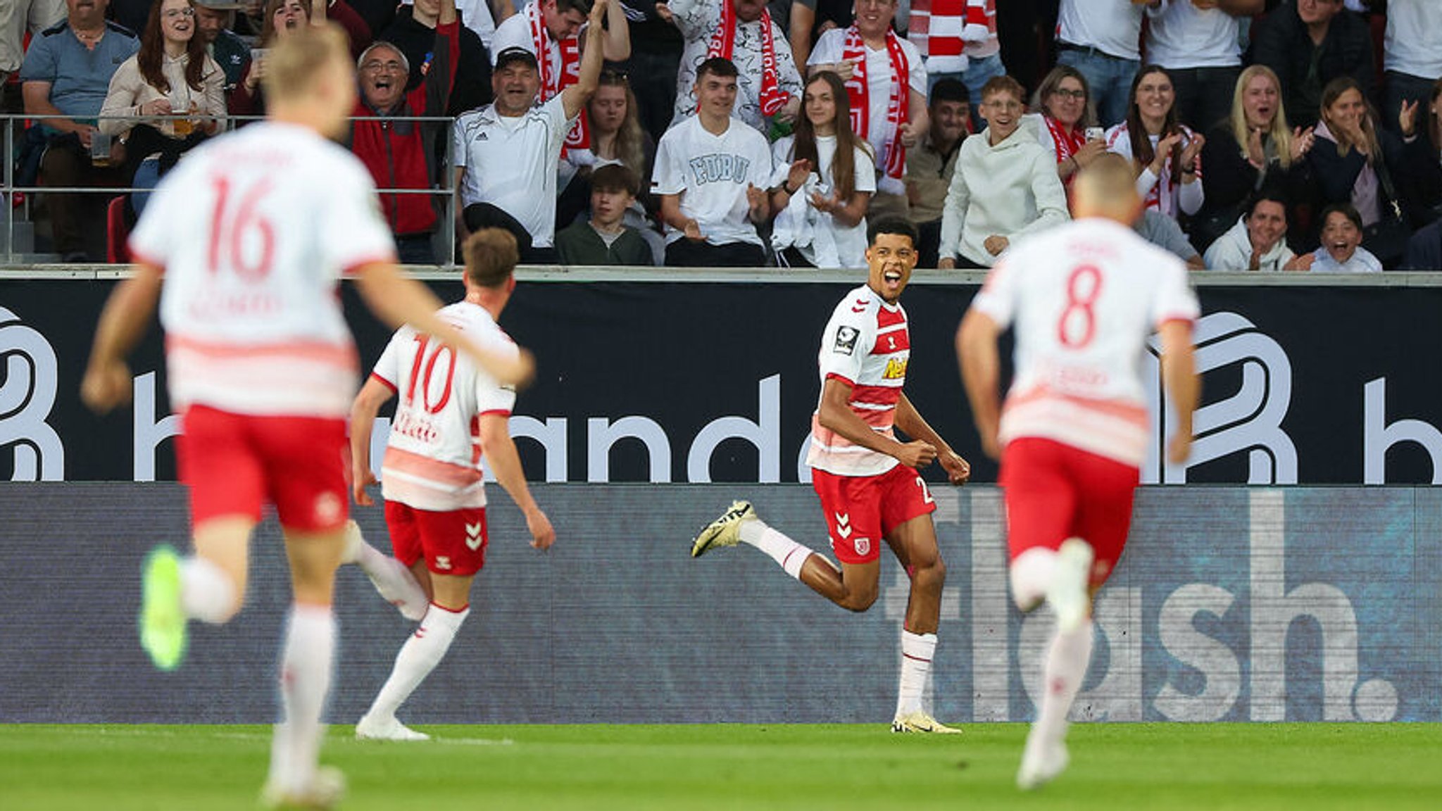 24.05.2024, Bayern, Regensburg: Fußball: 2. Bundesliga - Relegation, Jahn Regensburg - SV Wehen Wiesbaden, Relegation, Hinspiel, Jahnstadion Regensburg. Der Regensburger Noah Ganaus (M) jubelt nach seinem Tor zum 1:0. Foto: Daniel Löb/dpa - WICHTIGER HINWEIS: Gemäß den Vorgaben der DFL Deutsche Fußball Liga bzw. des DFB Deutscher Fußball-Bund ist es untersagt, in dem Stadion und/oder vom Spiel angefertigte Fotoaufnahmen in Form von Sequenzbildern und/oder videoähnlichen Fotostrecken zu verwerten bzw. verwerten zu lassen. +++ dpa-Bildfunk +++