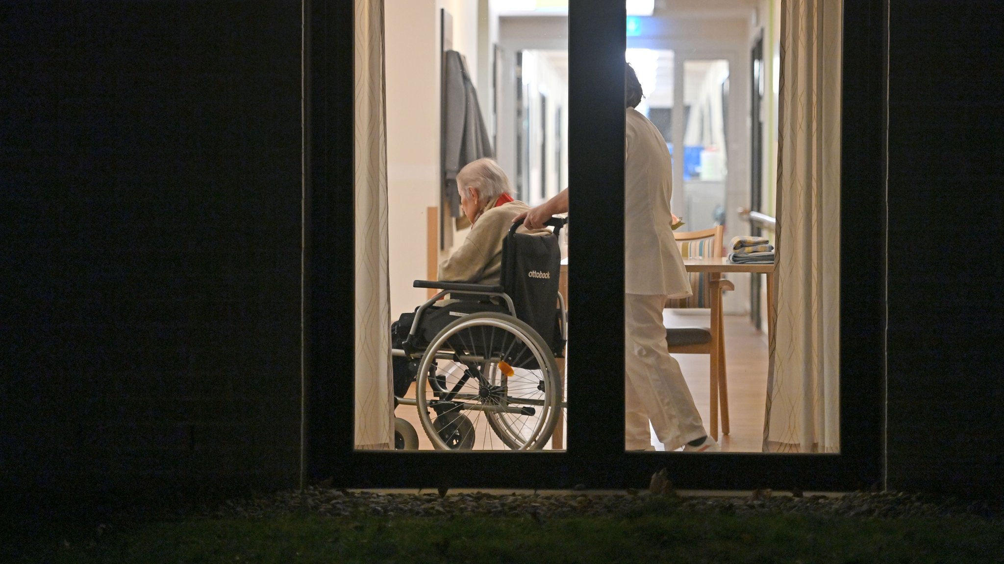 Senior im Rollstuhl mit Pflegerin