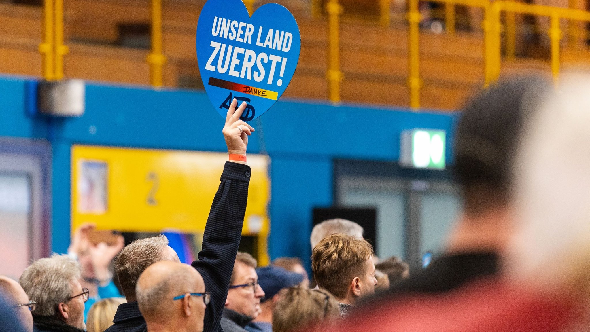 Ein Besucher hält in Rockenhausen bei einer AfD-Wahlkampfveranstaltung für die kommende Landtagswahl in Rheinland-Pfalz ein Schild mit der Aufschrift „Unser Land ZUERST!“ hoch. | Bild: dpa-Bildfunk/Laszlo Pinter Ein Besucher hält in Rockenhausen bei einer AfD-Wahlkampfveranstaltung für die kommende Landtagswahl in Rheinland-Pfalz ein Schild mit der Aufschrift „Unser Land ZUERST!“ hoch.