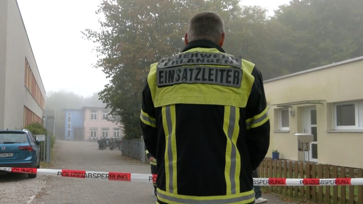 Ein Einsatzleiter steht vor dem Albert-Schweitzer-Gymnasium in Erlangen.