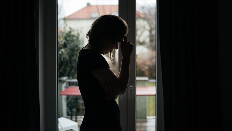 Silhouette einer einsamen Frau vor einem Fenster