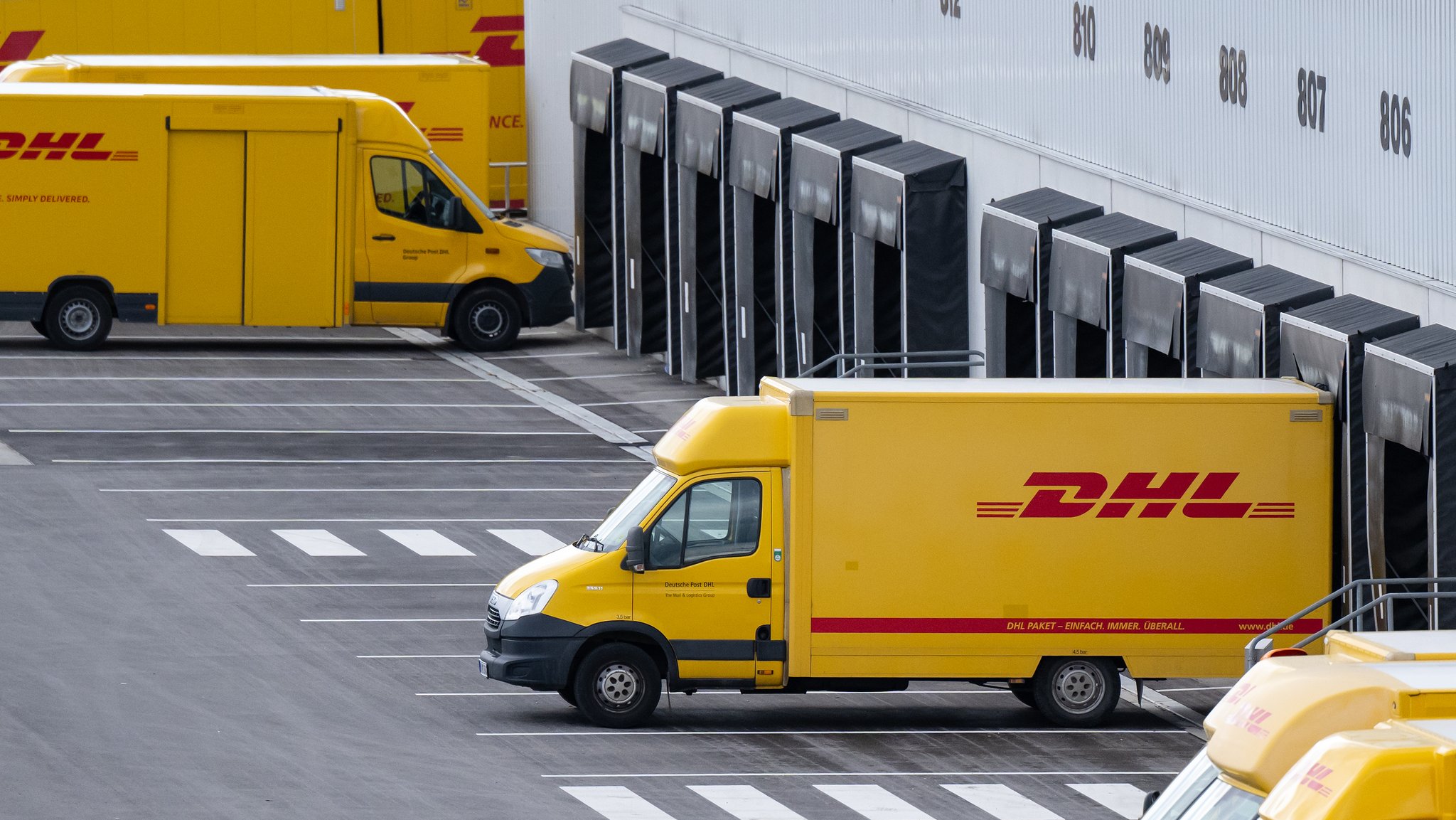 Container und Fahrzeuge mit dem Logo von DHL stehen an einem DHL-Paketzentrum (Archiv- und Symbolbild)