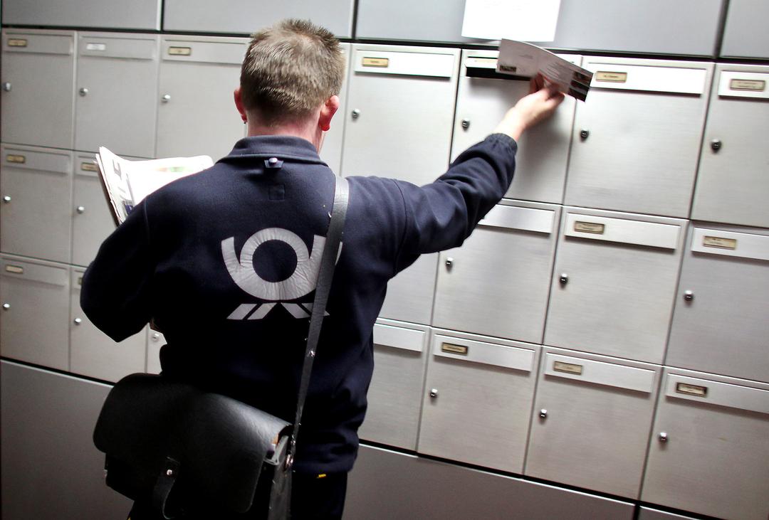 Ein Briefträger der Deutschen Post trägt Briefe aus (Archivbild)