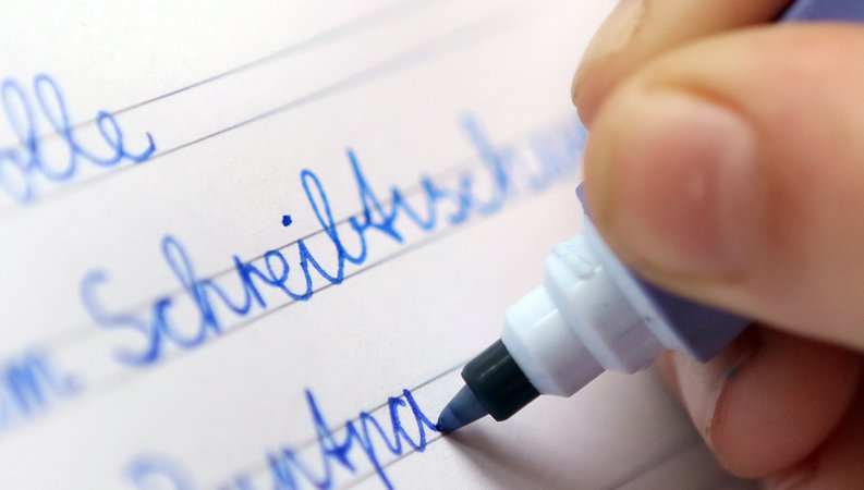 in Kind schreibt mit verbundener Schreibschrift, der Schulausgangsschrift, in ein Schulheft. | Bild: picture alliance / dpa | Stephanie Pilick in Kind schreibt mit verbundener Schreibschrift, der Schulausgangsschrift, in ein Schulheft.