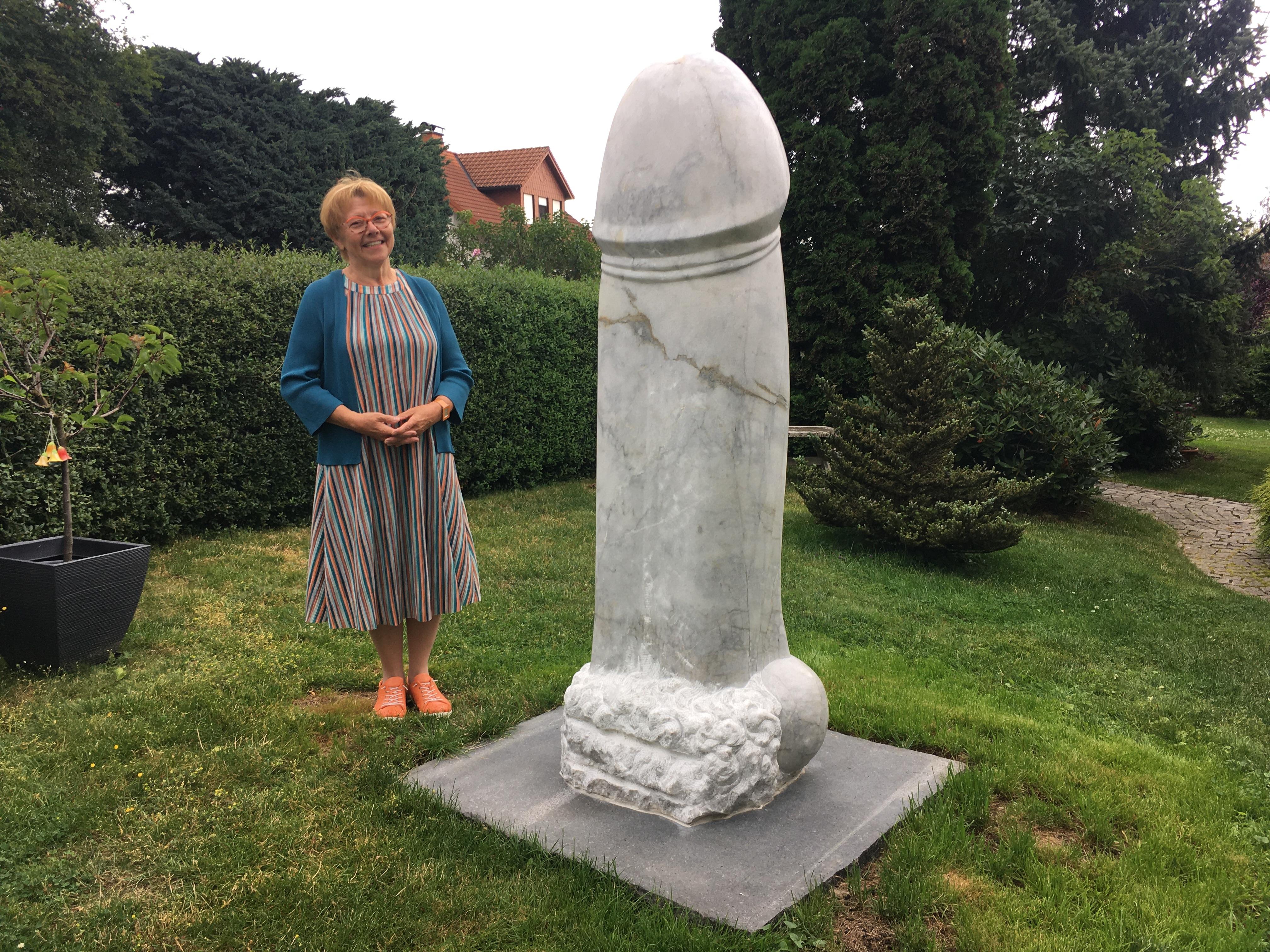 Ilona Vogel in ihrem garten in Köditz im Landkreis Hof vor dem riesigen Stein-Penis aus Wunsiedler Marmor.