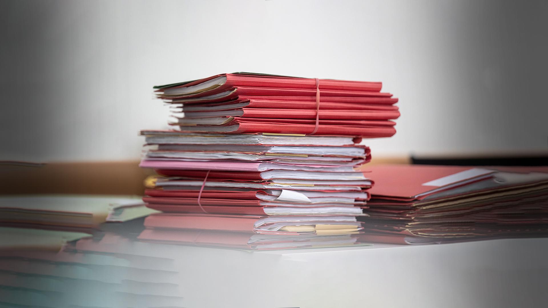Stapelweise Akten liegen verschnürt auf einem Tisch.