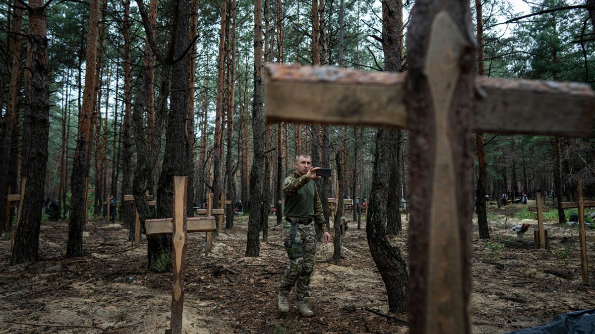 Oleh Kotenko, der Beauftragte für Vermisstenfragen unter besonderen Umständen, filmt mit seinem Smartphone die nicht identifizierten Gräber von Zivilisten und ukrainischen Soldaten, die von den russischen Streitkräften zu Beginn des Krieges getötet worden waren, im kürzlich zurückeroberten Gebiet von Isjum..