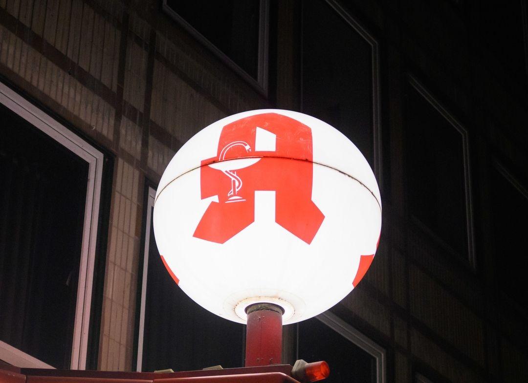Ein Logo einer Apotheke leuchtet auf einer runden Kugel.