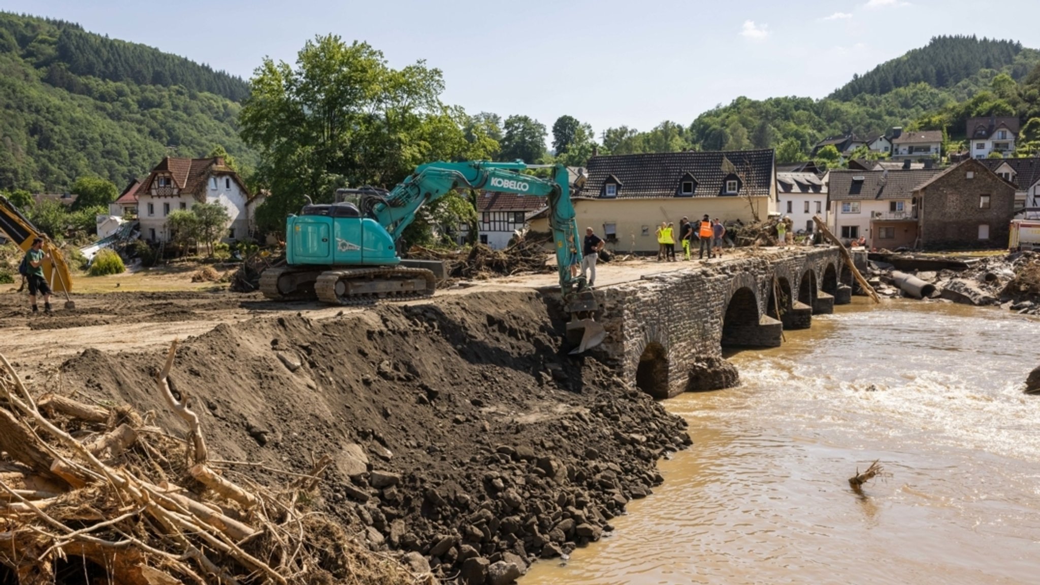 18.07.2021, Rheinland-Pfalz, Ahrbrück: Ein Bagger verdichtet eine notdürftig geflickte Brücke über den Fluss Ahr.