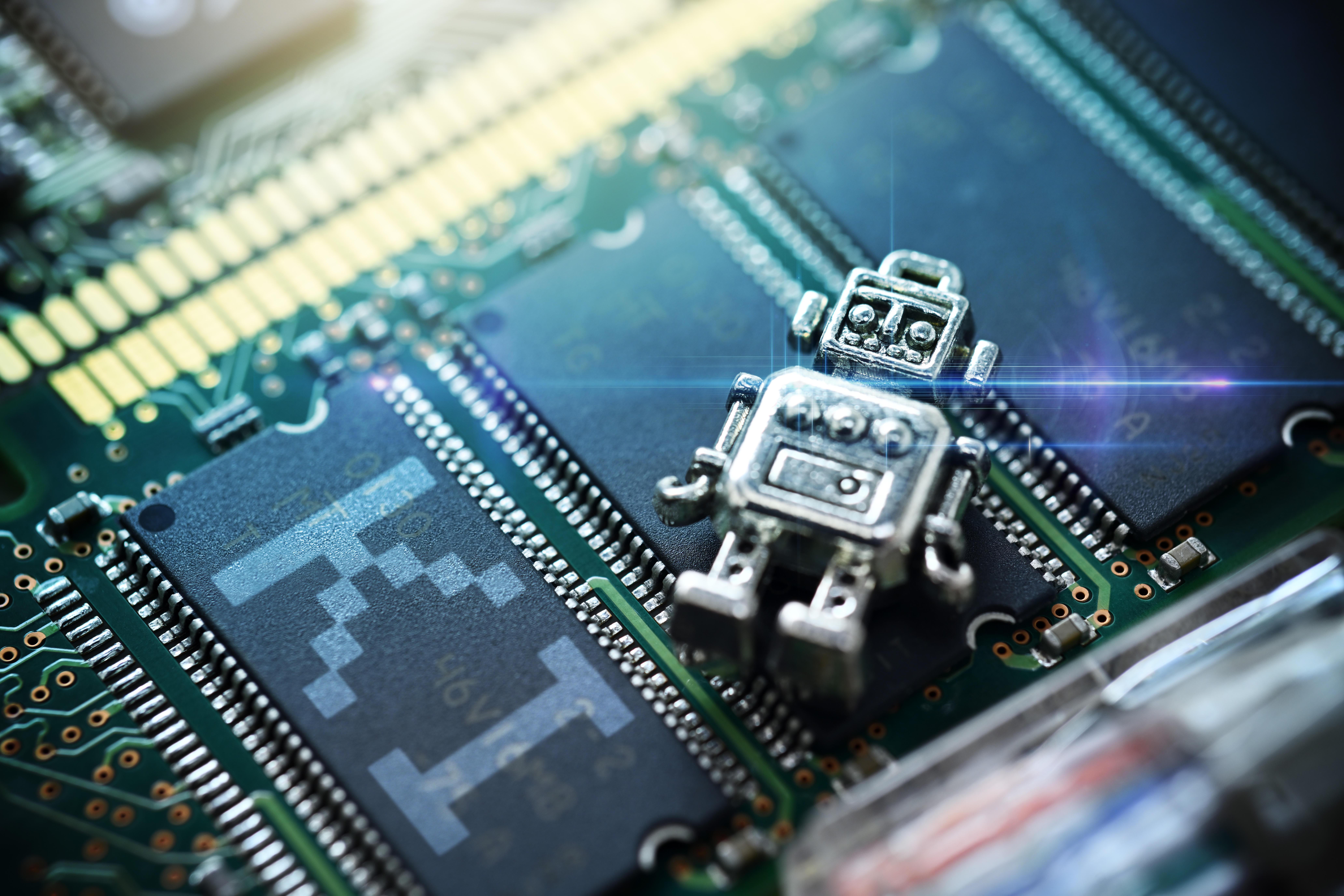 Miniatur-Roboter auf einer Computerplatine mit Schriftzug KI, Symbolfoto Künstliche Intelligenz 