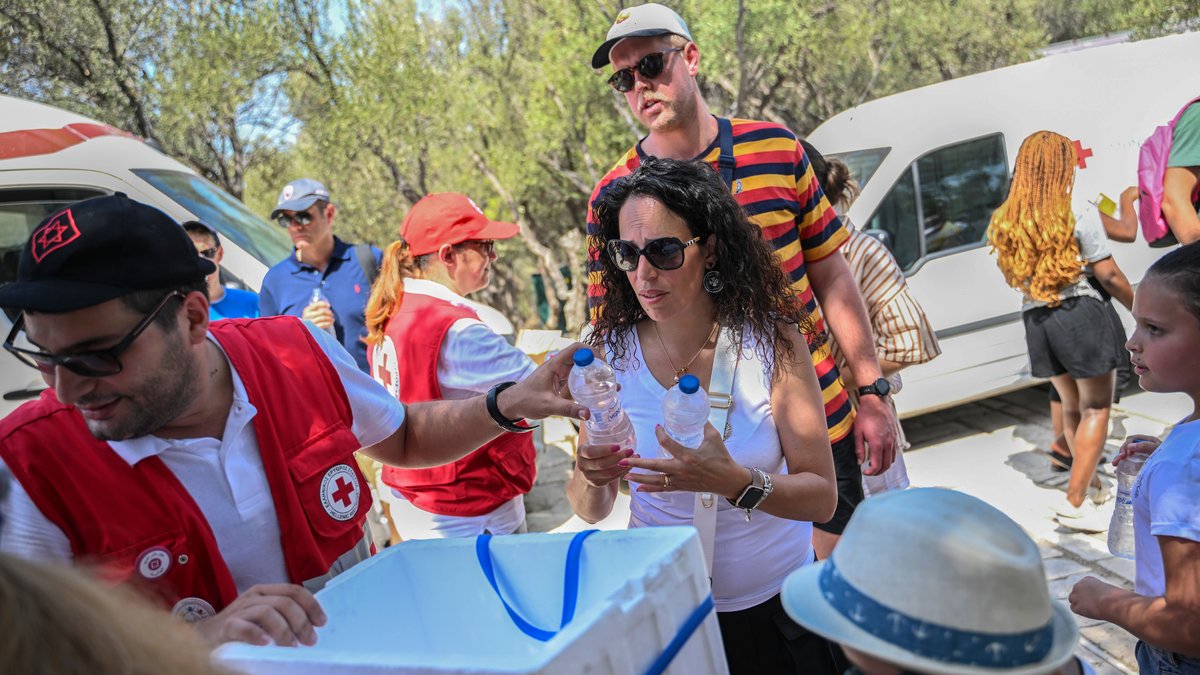 Mitarbeiter des Griechischen Roten Kreuzes verteilen vor der Akropolis Wasserflaschen an die Besucher. Das Kulturministerium hat beschlossen, die archäologische Stätte während der heißesten Stunden des Tages, von 12 bis 17 Uhr, zu schließen, da Griechenland von einer Hitzewelle betroffen ist.