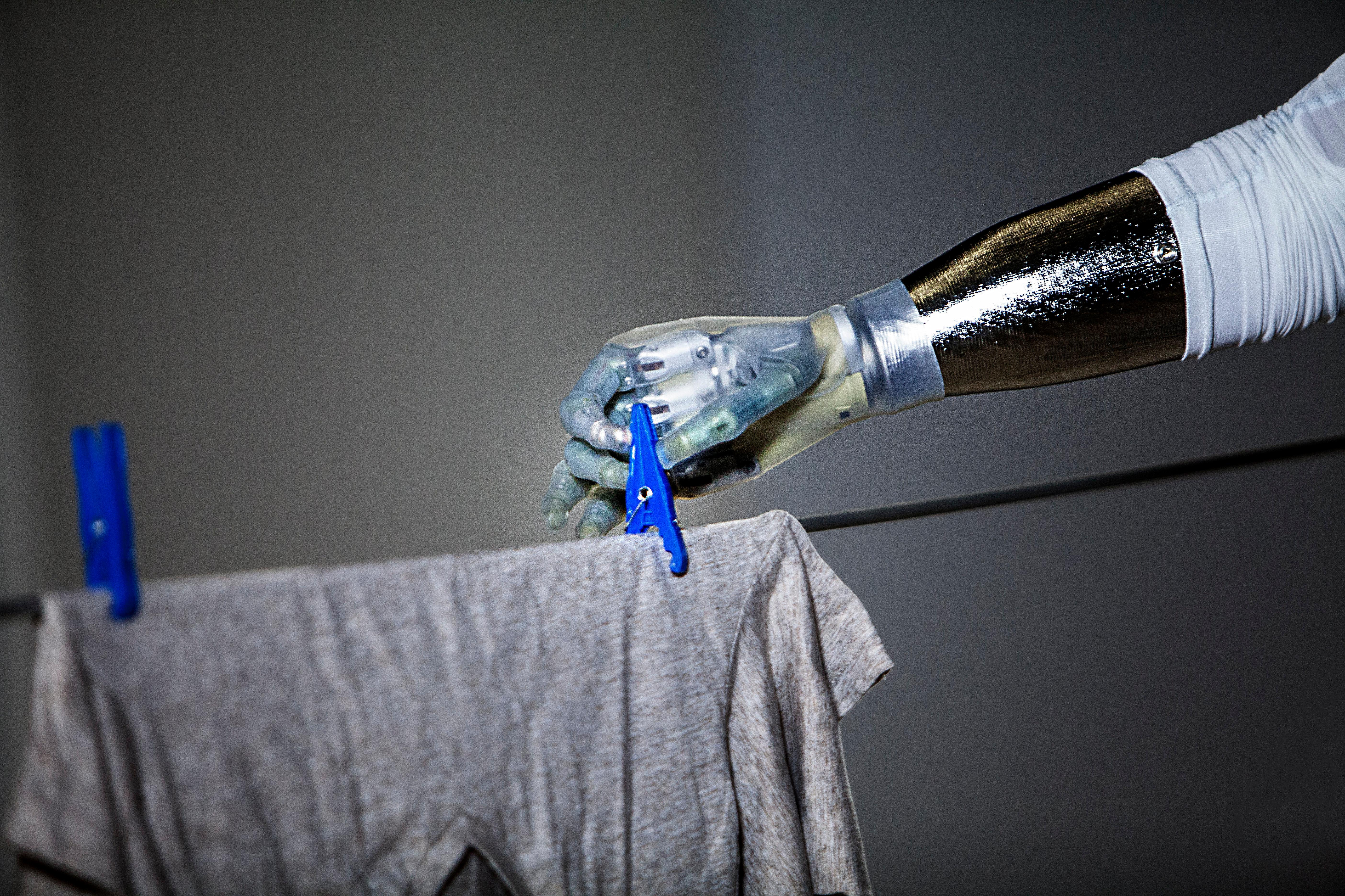 Roboterhand befestigt ein T-Shirt mit einer Wäscheklammer an der Leine